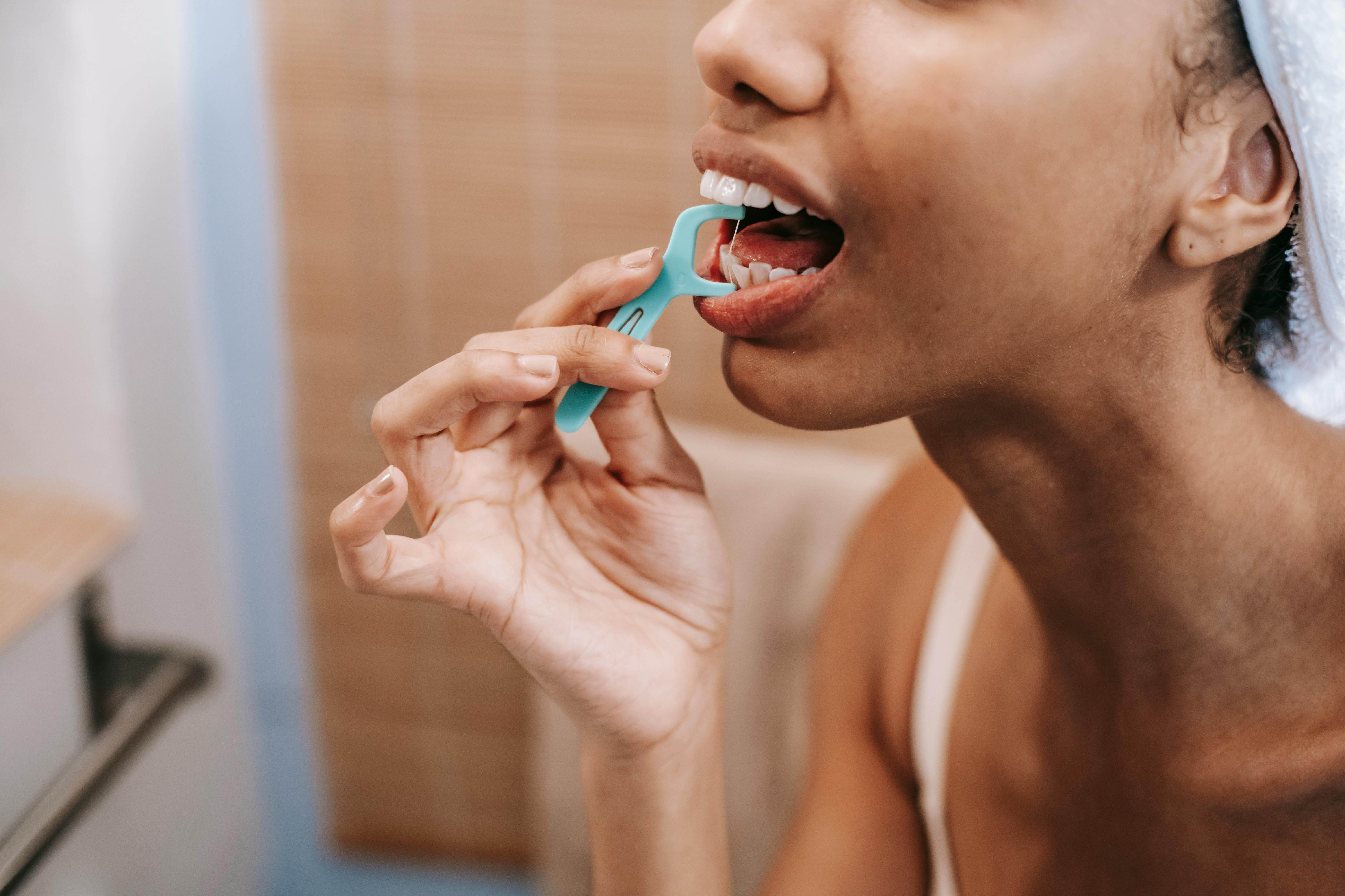 person using dental floss pick best oral hygiene products kneib dentistry