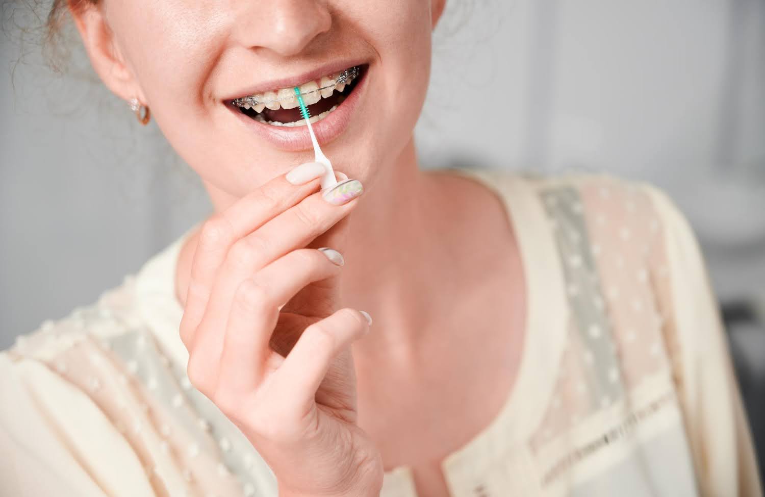 woman using interdental brush to clean braces kneib dentistry best oral hygiene products